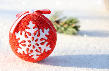 Christmas toy red ball with a snowflake and a pine branch with cones in the snow