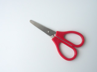 Stainless scissors with red plastic handle is isolated on the white background. 