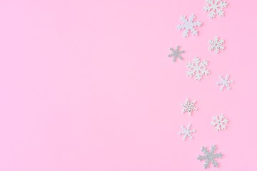 Pink Christmas background with white and silver snowflakes border and empty space for  text, selective focus. New year flat lay with snowflakes decorative border. Winter postcard. 