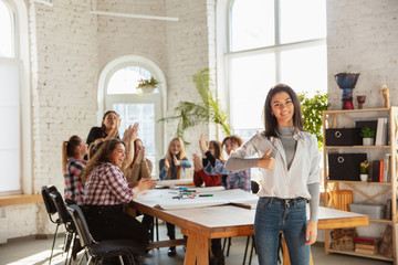 Women's rights and equality at the office. Caucasian businesswomen or young confident model with thumb up in front of coworkers having meeting about problem in workplace, male pressure and harassment.