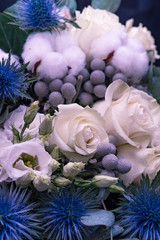 Winter wedding bouquet of white roses, cotton and eringium on a black background. The bride's bouquet.