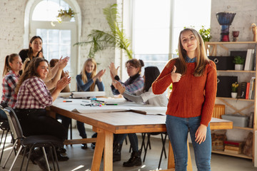 Women's rights and equality at the office. Caucasian businesswomen or young confident model with thumb up in front of coworkers having meeting about problem in workplace, male pressure and harassment.
