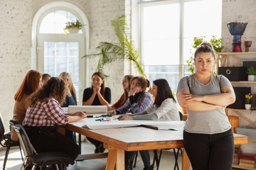Women's rights and equality at the office. Caucasian businesswomen or young confident model crossed hands in front of coworkers having meeting about problem in workplace, male pressure and harassment.