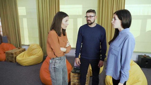 girls members of team argue emotionally about business problems and guy tries to reconcile quarreling colleagues in coworking office slow motion