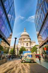 Fototapeta na wymiar St Paul Cathedral in London with car street vendor and modern buildings reflections on a sunny day