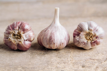 Garlic lie in a row on a rustic wooden background. Copy, empty space for text