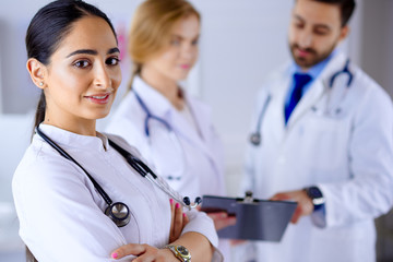 Attractive female arab doctor smiling in front of medical stuff in hospital