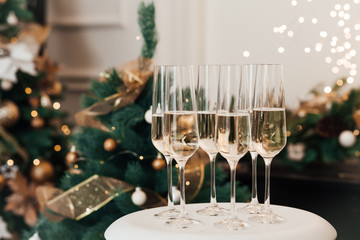 Christmas and New Year celebration with champagne. New Year holiday decorated. Six champagne glasses on the background of Christmas tree lights