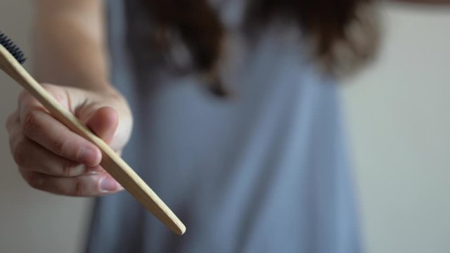 Closeup at woman hand is showing Bamboo toothbrush.Zero waste, bathroom, plastic free