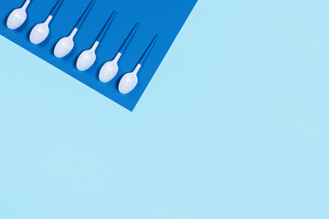 Pattern of white spoons on two-toned blue background. Flat lay, top view.
