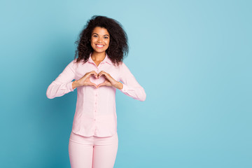 Obraz premium Photo of pretty dark skin wavy lady making heart figure symbol with hands cardiology protection safety wear pink shirt trousers isolated blue color background