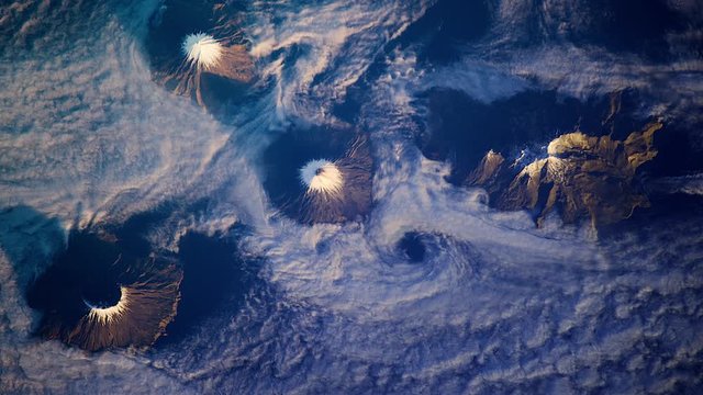Moving cloudes aerial satellite view of volcanoes chain in Alaska Aleutian island sunrise animation. Contains public domain image by Nasa