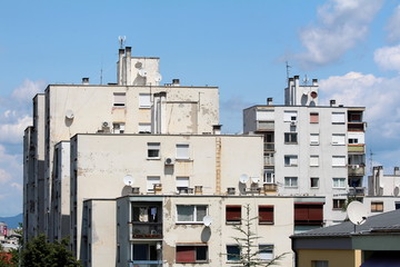 White dilapidated apartment buildings in old part of town with multiple satellite dishes and...