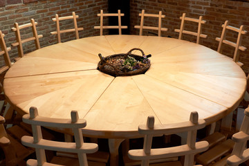 Empty round wooden table with white oak chairs in the interior of a wine cellar pub (restaurant, bar)