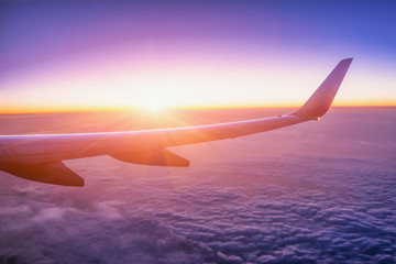Airplane wing with sunrise in light flare by looking through the airplane window. - Image