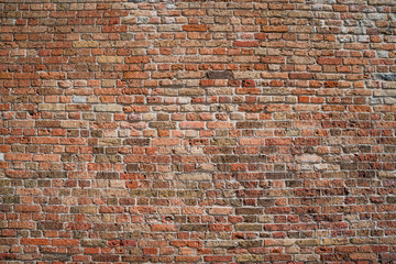 Texture of a medieval brick wall of burgundy, red and brown bricks.  General view.