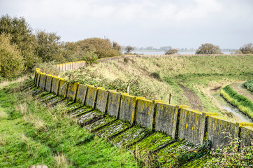 Fototapeta na wymiar Grassy dike on the north coast of the island of Schouwen-Duiveland, The Netherlands with the weathered concrete of the former sea defense