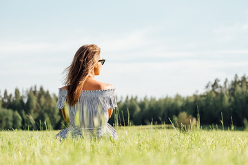 Woman wearing dress sitting on green grass field