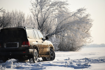 An SUV car riding in a field covered with snow off-road.