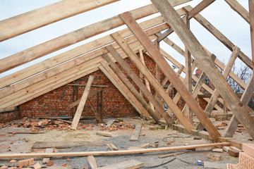 Fototapeta na wymiar Unfinished house rooftop roofing construction attic trusses, wooden beams, eaves, timber. House roof wooden frame construction.