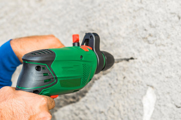 a professional mason is drilling into a concrete by his heavy duty drill machine 