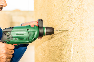 a professional mason is drilling into a concrete by his heavy duty drill machine 