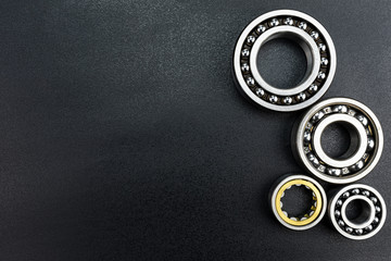 Ball bearing lying on a black background with copy space on the left side, flat view from above.