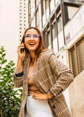 Attractive woman with long hair with glasses smiles while talking on the phone.