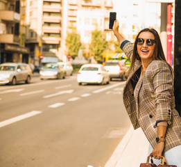 Attractive woman with long hair has a smartphone in her hand and calls a taxi.