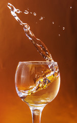 Glass with alcoholic beverage and splashes with liquid drop