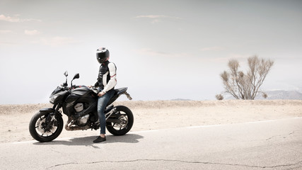 Long shot of a motorcyclist man sitting on motorbike