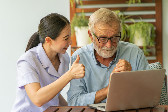 Young Nurse Take Care Senior Man At Home, Senior Man With Nurse Are Checking Health Results Online By Laptop, Health Care Concept