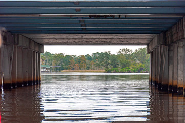 Under a bridge with a view of its columns, metal parts and water, near Jacksonville, Florida, USA