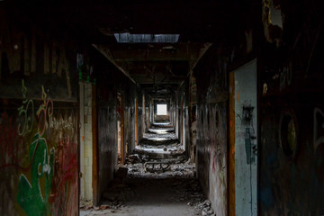 corridor in an abandoned building with rubble and graffiti painted walls lights and shadows rooms