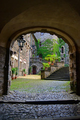 view from behind an arch of the inner courtyard of a castle in germany with ivy by the walls in a sunny day