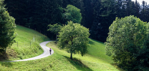 Cyclist riding a lonly road in the green emmental valley in Switzerland