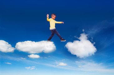 Fototapeta na wymiar Little boy walking from one cloud to another