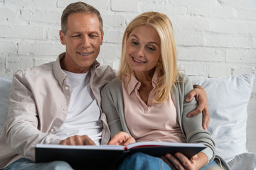 Smiling couple looking at notebook while sitting on bed