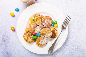 Poffertjes. Little Dutch pancakes with colorful powdered sugar and candies. Top view, flat lay, copy space.