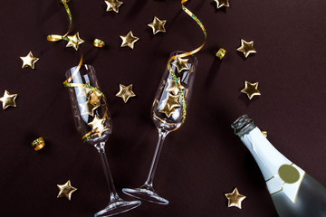 Champagne glasses and star confetti on a dark background top view