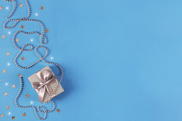 Christmas background with gift box and sparkling decorations on the blue background of the canvas.
