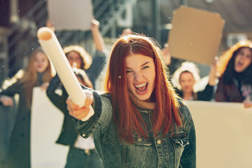 Young woman screaming in front of people protesting about women's rights and equality on the...