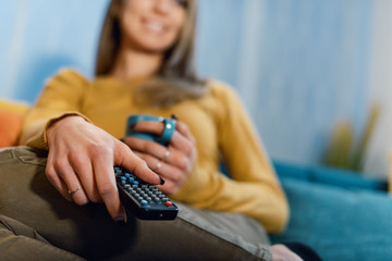 Woman holding a remote control and watching TV