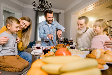 Family celebrating Christmas or Thanksgiving day. Happy smiling father serving food, cutting roasted turkey.