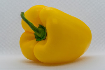 Yellow pepper with a green ponytail on a white background