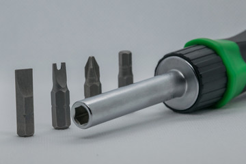  Professional screwdriver with four different nozzles on a white background. The last nozzles as well as the background of the screwdriver are blurred