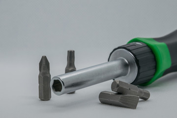 Professional screwdriver with four nozzles, two of which lie horizontally on a white background. The last nozzle as well as the background of the screwdriver is blurred