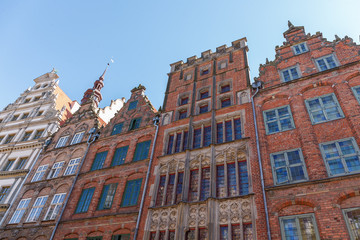 Fototapeta premium Building facades of red brick houses on sky background, bottom view on a sunny day