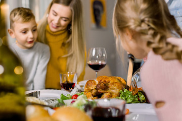 Naklejka na ściany i meble Happy Thanksgiving Day or Merry Christmas. Family sitting at the table and celebrating holiday. Young mother and two children boy and girl. Traditional dinner.