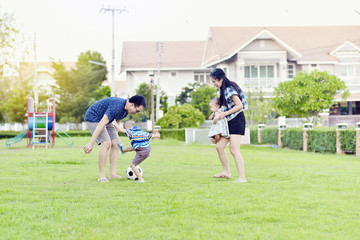 Portrait of Asian family playing football together in garden